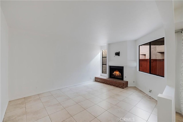 7211 Cozycroft Ave Unit 19, Winnetka, CA 91306 - unfurnished living room featuring a warm lit fireplace, light tile patterned flooring, and baseboards