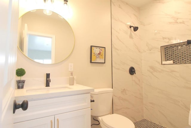 full bathroom featuring a tile shower, toilet, and vanity