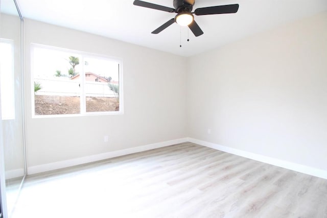 empty room with wood finished floors, a ceiling fan, and baseboards