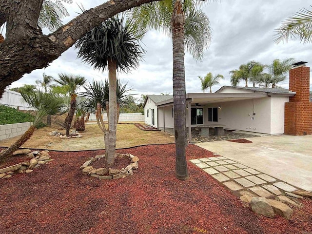 view of yard with fence, a patio area, and an attached carport