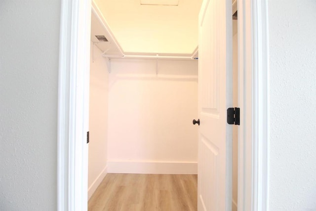 walk in closet with light wood-style floors