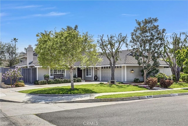 view of front facade featuring a garage, a front yard, concrete driveway, and fence