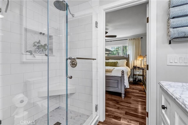 ensuite bathroom featuring wood finished floors, a ceiling fan, vanity, a stall shower, and ensuite bathroom