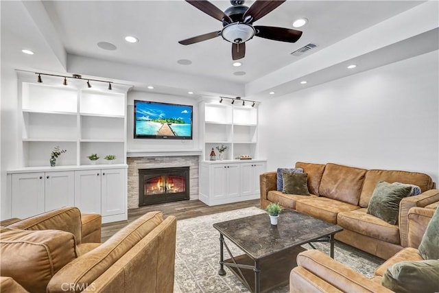 living room with a ceiling fan, a stone fireplace, light wood-style floors, visible vents, and recessed lighting