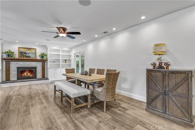 dining area featuring a ceiling fan, a stone fireplace, light wood finished floors, visible vents, and recessed lighting