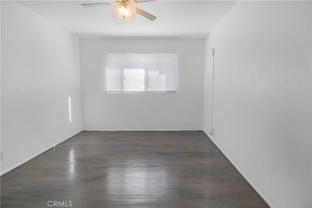 spare room with wood finished floors, a ceiling fan, and baseboards