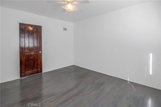 unfurnished room featuring dark wood finished floors, baseboards, a ceiling fan, and visible vents