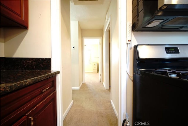 73203 Sun Valley Dr Unit 29, Palms, CA 92277 - kitchen with gas range oven, reddish brown cabinets, light carpet, and dark stone countertops