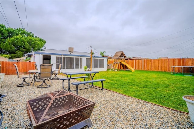 1924 Hunter Rd, Colton, CA 92324 - fenced backyard featuring a playground, a fire pit, a trampoline, and a sunroom