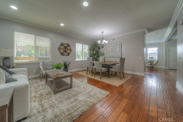 living area featuring baseboards, a wealth of natural light, wood finished floors, and a chandelier