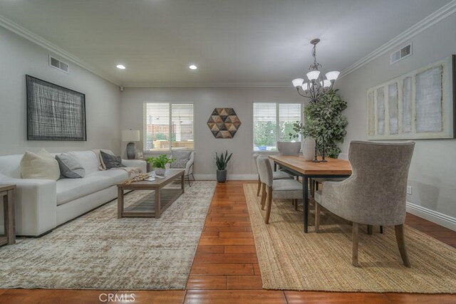 interior space featuring crown molding, a chandelier, visible vents, and wood-type flooring