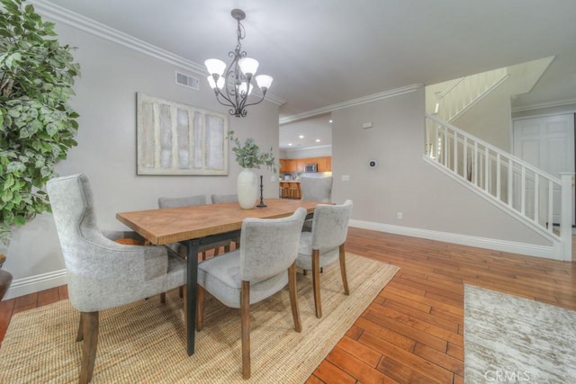 dining space with visible vents, stairs, hardwood / wood-style flooring, and an inviting chandelier