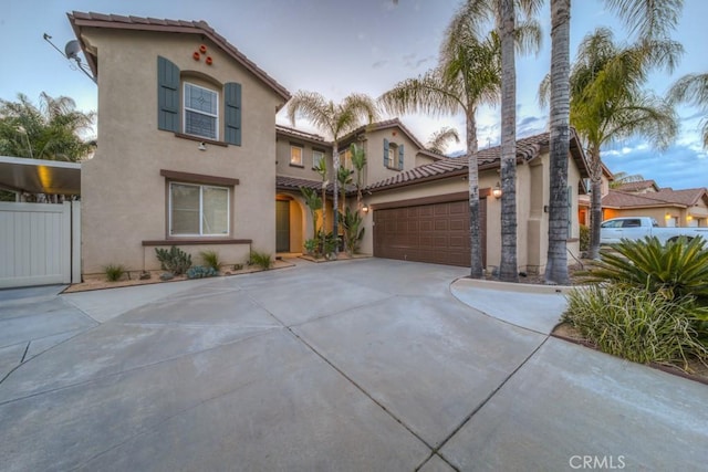 mediterranean / spanish home with an attached garage, stucco siding, and concrete driveway