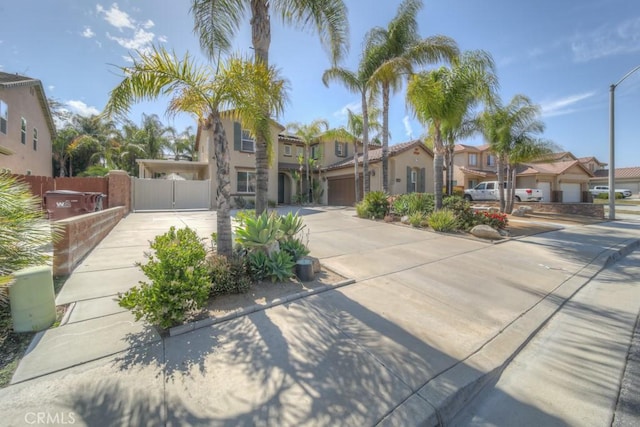 mediterranean / spanish house featuring a residential view, a gate, driveway, and fence