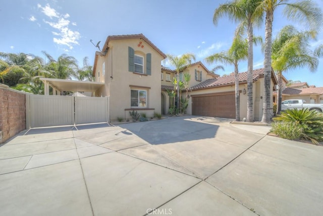 mediterranean / spanish-style house with an attached garage, stucco siding, a gate, a tiled roof, and driveway