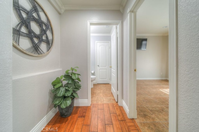 hall with crown molding, baseboards, and wood finished floors