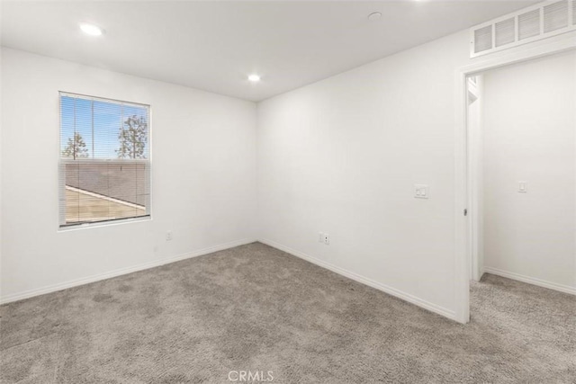 carpeted spare room featuring baseboards, visible vents, and recessed lighting