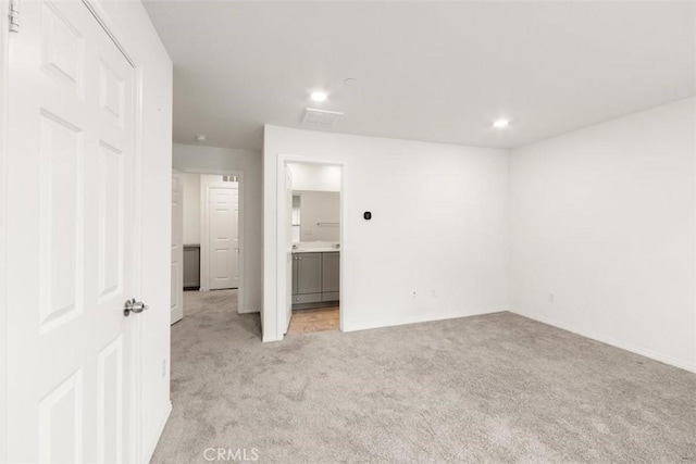 unfurnished bedroom with ensuite bath, baseboards, recessed lighting, and light colored carpet