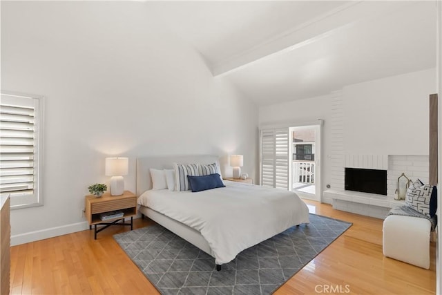 bedroom featuring lofted ceiling with beams, access to exterior, multiple windows, and wood finished floors