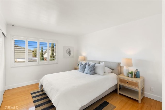 bedroom featuring light wood finished floors and baseboards