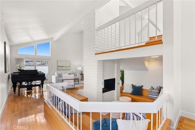 living area with a fireplace, baseboards, high vaulted ceiling, and wood-type flooring