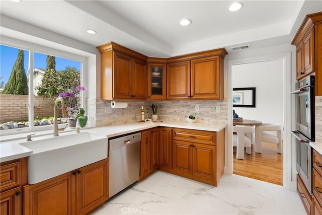 kitchen featuring visible vents, brown cabinets, appliances with stainless steel finishes, and a sink