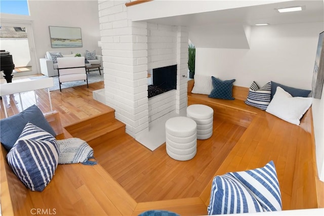 living area featuring a brick fireplace and wood-type flooring