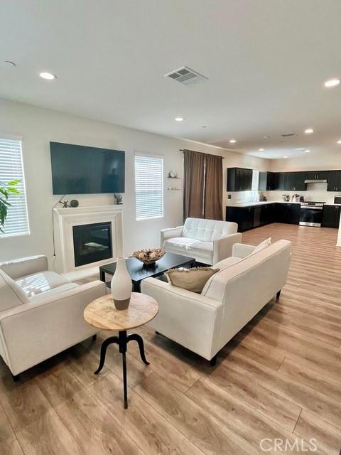 2819 La Calle Sabio Ave, Rosamond, CA 93560 - living area featuring light wood-type flooring, recessed lighting, and a glass covered fireplace