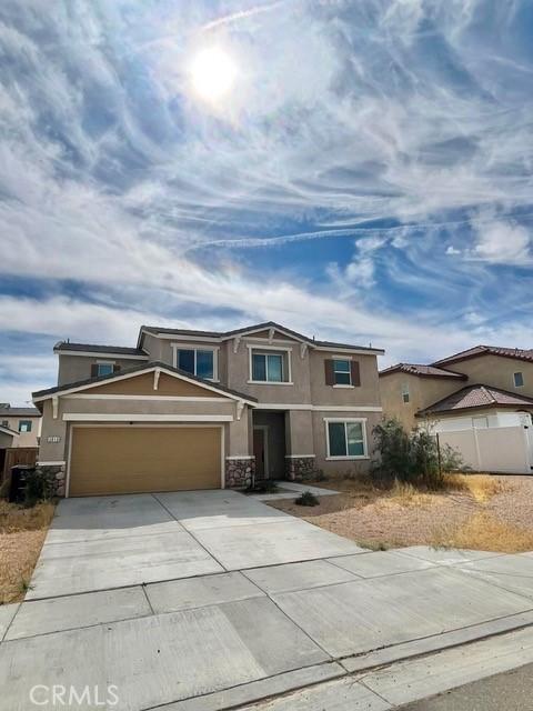 2819 La Calle Sabio Ave, Rosamond, CA 93560 - view of front facade with stone siding, stucco siding, a garage, and driveway
