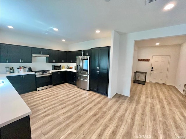 2819 La Calle Sabio Ave, Rosamond, CA 93560 - kitchen featuring appliances with stainless steel finishes, under cabinet range hood, light countertops, light wood-type flooring, and recessed lighting