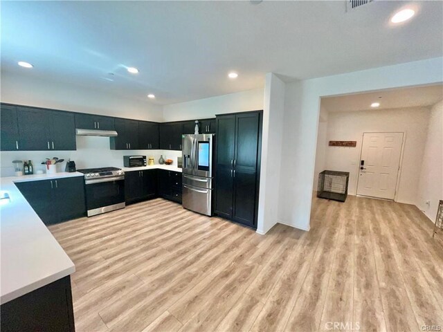 2819 La Calle Sabio Ave, Rosamond, CA 93560 - kitchen featuring appliances with stainless steel finishes, under cabinet range hood, light countertops, light wood-type flooring, and recessed lighting