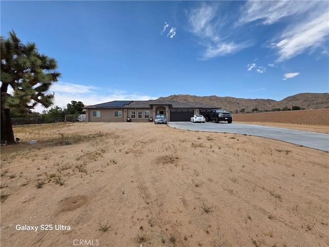 24236 Cahuilla Rd, Apple Valley, CA 92307 - view of front facade with roof mounted solar panels, a mountain view, concrete driveway, and an attached garage
