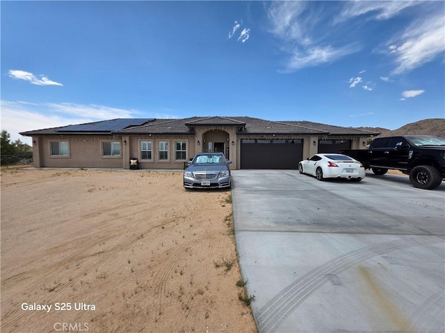 24236 Cahuilla Rd, Apple Valley, CA 92307 - view of front facade featuring an attached garage, solar panels, driveway, and stucco siding