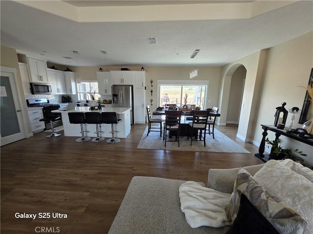 24236 Cahuilla Rd, Apple Valley, CA 92307 - living area with arched walkways, dark wood-style flooring, and baseboards