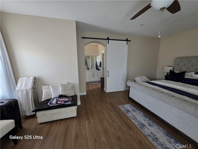 24236 Cahuilla Rd, Apple Valley, CA 92307 - bedroom with a barn door, arched walkways, wood finished floors, ensuite bathroom, and a ceiling fan