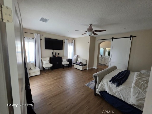 24236 Cahuilla Rd, Apple Valley, CA 92307 - bedroom with wood finished floors, arched walkways, a barn door, a textured ceiling, and ceiling fan