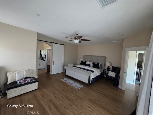 24236 Cahuilla Rd, Apple Valley, CA 92307 - bedroom featuring a barn door, wood finished floors, arched walkways, baseboards, and independent washer and dryer