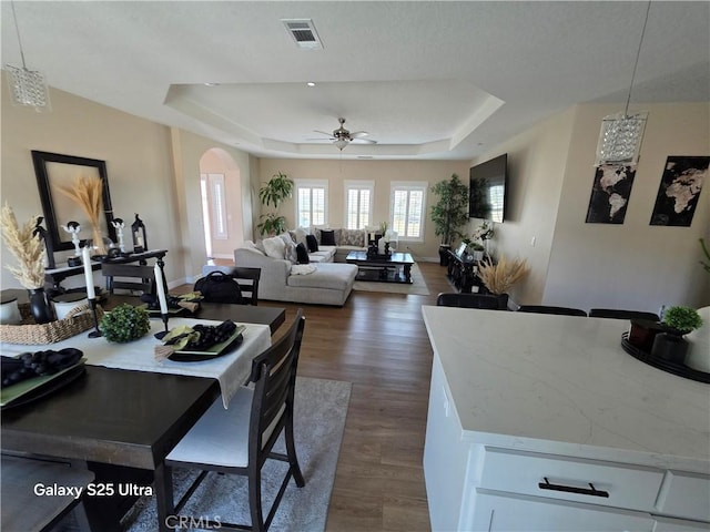 24236 Cahuilla Rd, Apple Valley, CA 92307 - dining area with a tray ceiling, arched walkways, a ceiling fan, and dark wood finished floors