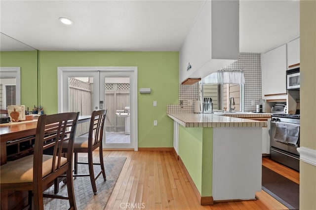 11 Northwind Ct Unit 41, Newport Beach, CA 92663 - kitchen with appliances with stainless steel finishes, white cabinetry, a peninsula, light wood finished floors, and recessed lighting