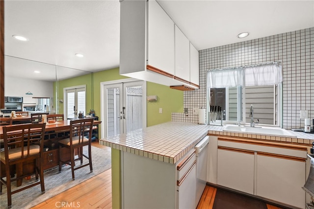 11 Northwind Ct Unit 41, Newport Beach, CA 92663 - kitchen featuring light wood-type flooring, white cabinetry, tile countertops, white dishwasher, and a peninsula