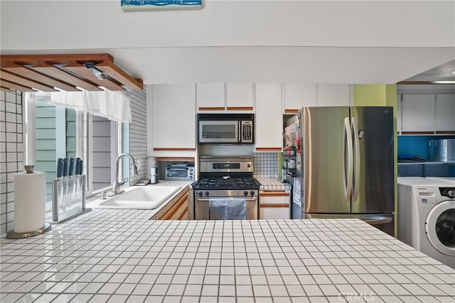 11 Northwind Ct Unit 41, Newport Beach, CA 92663 - kitchen featuring stainless steel appliances, tile counters, washer / dryer, white cabinets, and backsplash