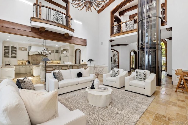 5015 Rancho Quinta Bnd, San Diego, CA 92130 - living area featuring a chandelier, a high ceiling, stone tile flooring, and arched walkways