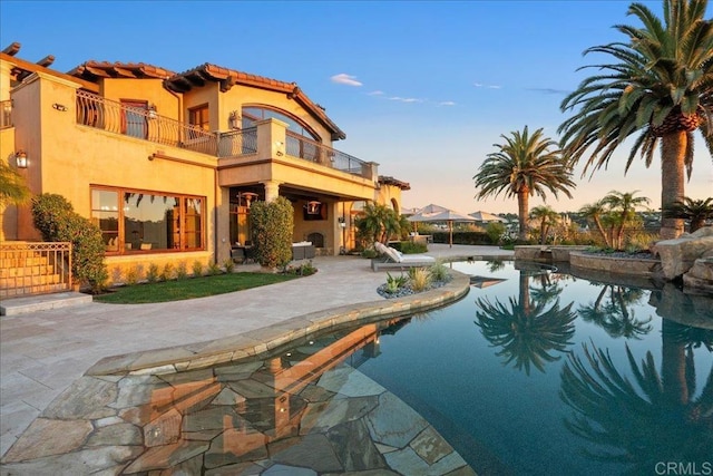5015 Rancho Quinta Bnd, San Diego, CA 92130 - rear view of house featuring a balcony, a patio, stucco siding, a tile roof, and an outdoor pool