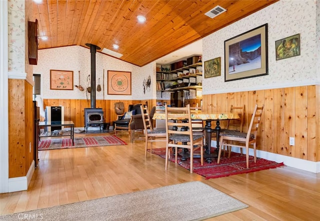 dining area featuring wooden walls, a wainscoted wall, wood-type flooring, and wallpapered walls