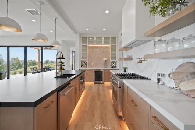 kitchen with a sink, light wood-style floors, visible vents, appliances with stainless steel finishes, and wine cooler