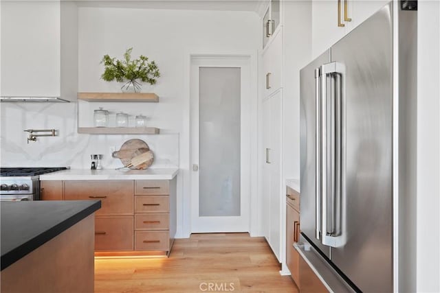 kitchen featuring backsplash, open shelves, modern cabinets, light wood-type flooring, and high quality appliances