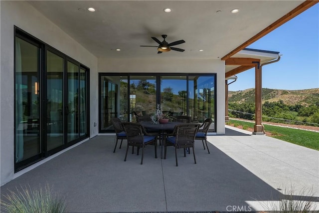 view of patio / terrace with outdoor dining space, ceiling fan, and a mountain view