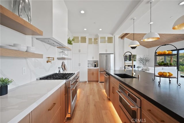 kitchen with light wood finished floors, open shelves, a sink, pendant lighting, and high quality appliances