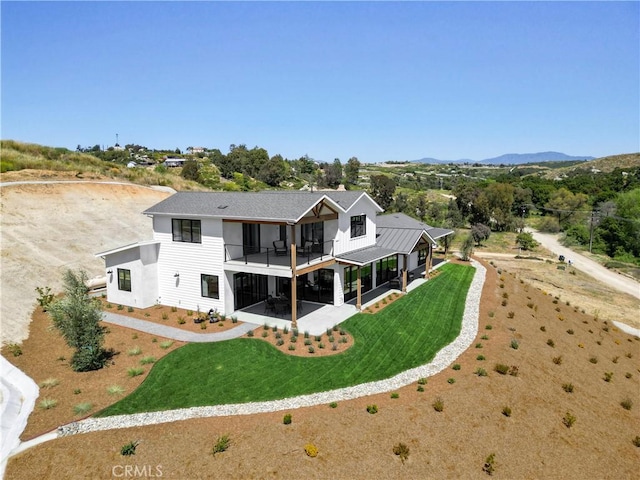 rear view of house with a patio area, driveway, a balcony, and a yard