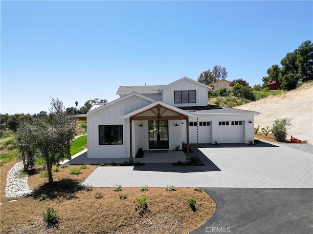 modern inspired farmhouse with board and batten siding, french doors, driveway, and an attached garage